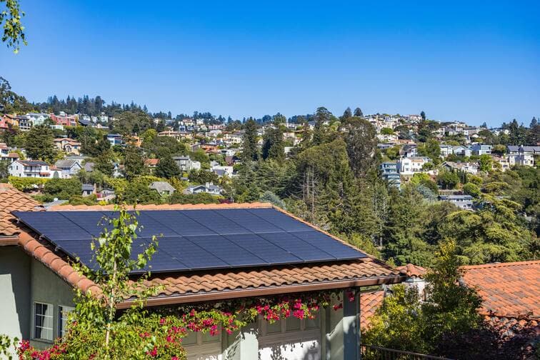 Black solar panels on the tiled roof of a brick home