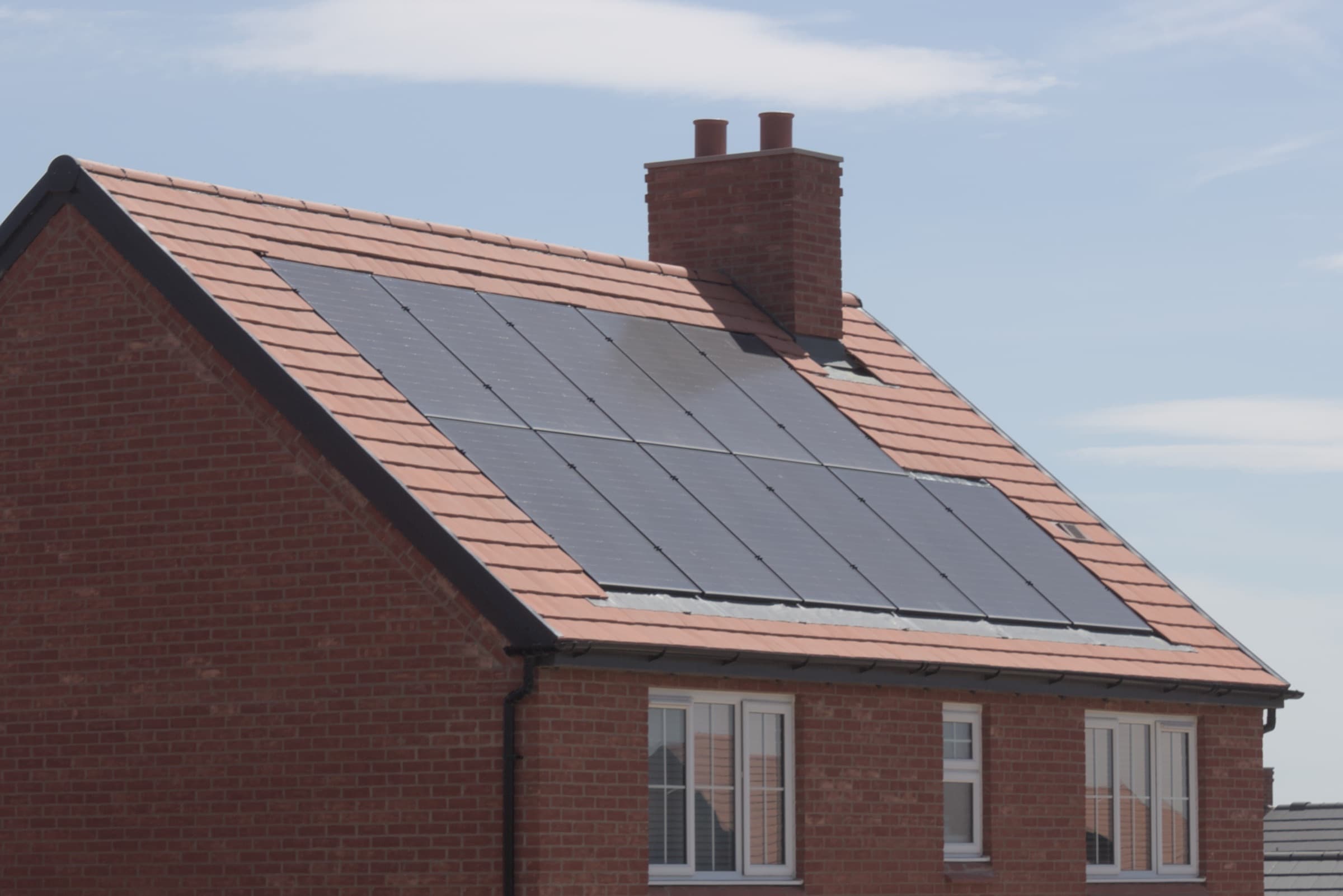 Black solar panels on the tiled roof of a brick home
